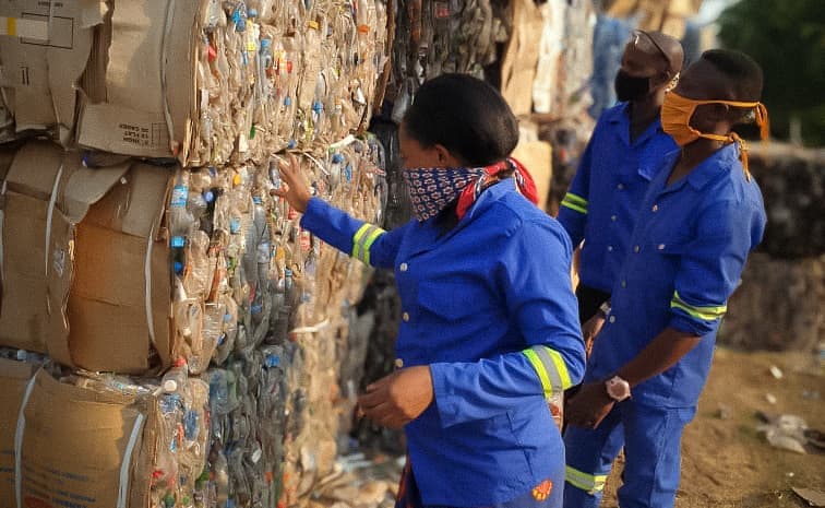 Staff standing by bales of recycled plastic