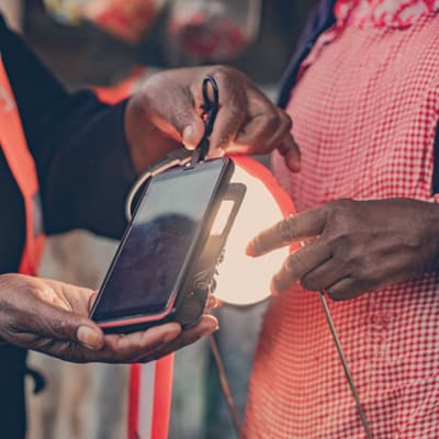 A man showing a woman how to charge a phone with solar power