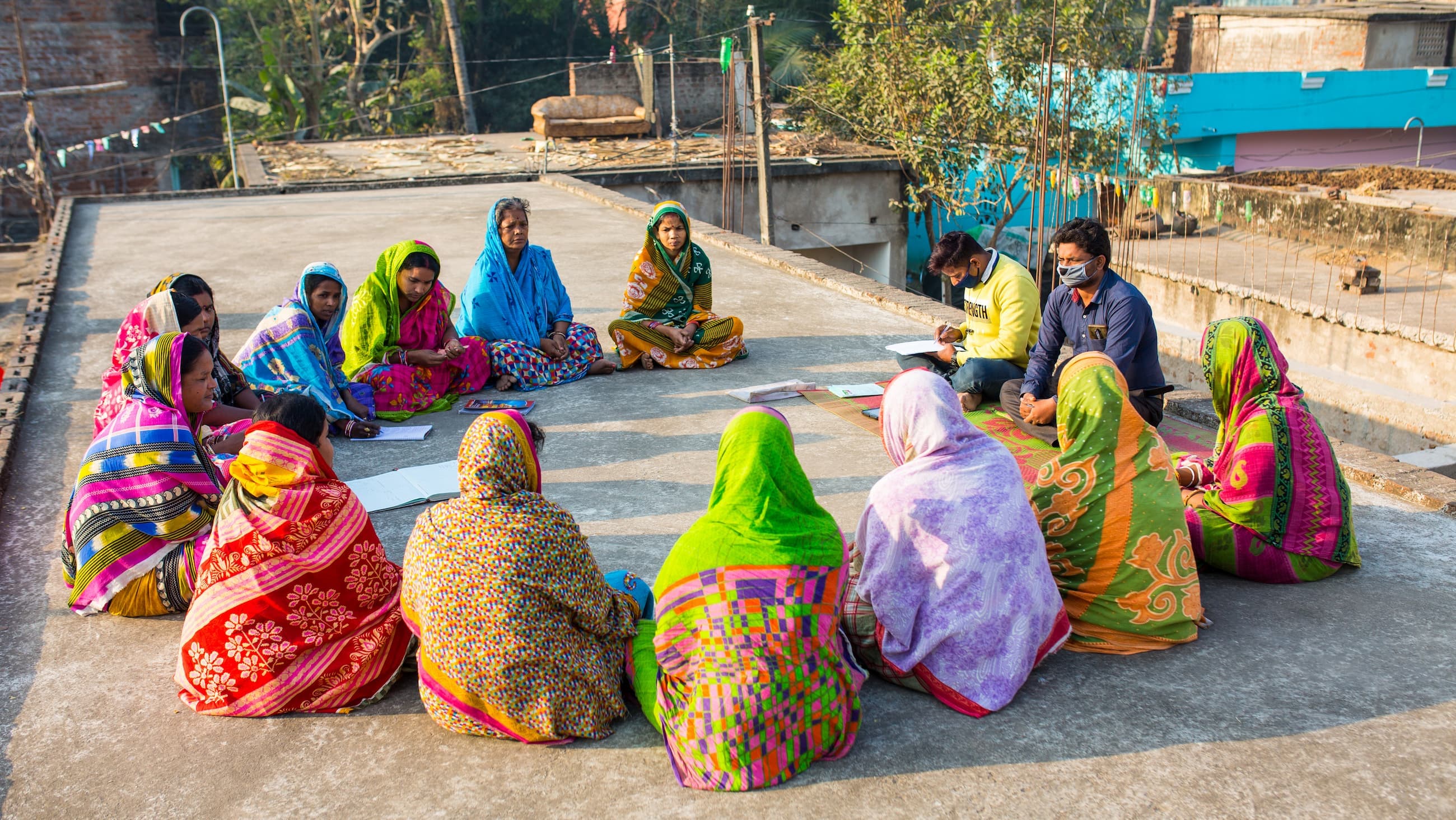 Women sit in a circle on the ground having a meeting