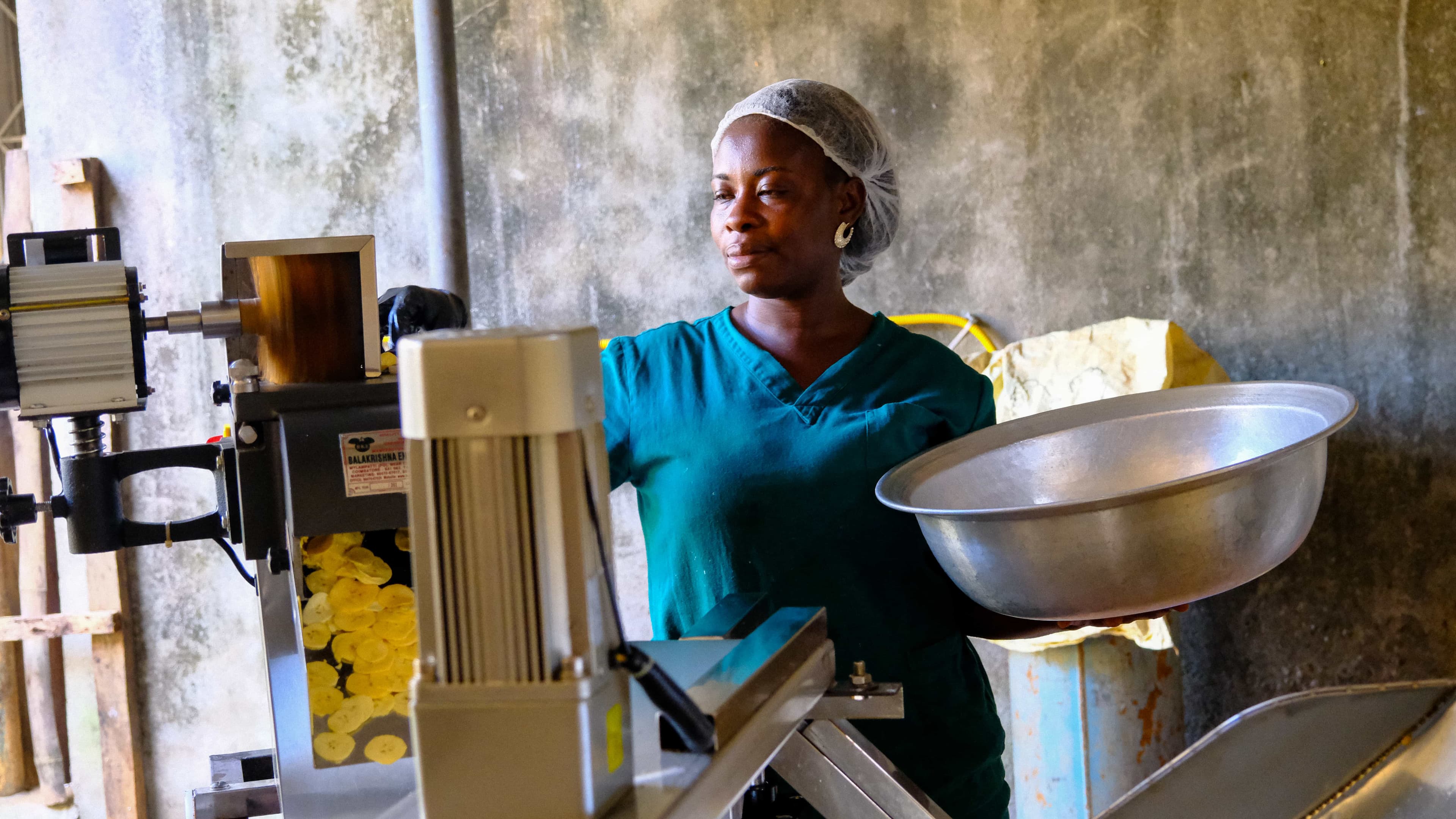 Woman with hairnet standing by a machine